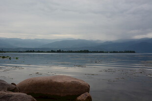 湖畔巨石与远方阴云景色