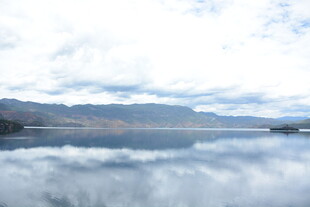 平静湖面倒映蓝天白云山峦