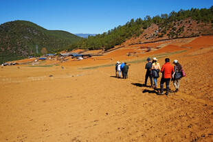 徒步者穿行于开阔黄土地