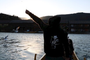 男子于船头指向远方