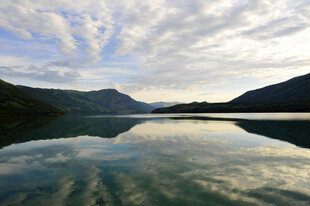 宁静湖水映蓝天白云山峦
