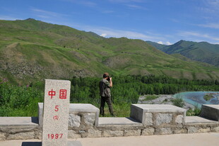 男子立于石碑前赏山水景