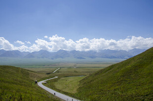 山间公路蜿蜒于绿野蓝天