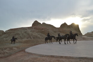 沙漠驼队行于壮丽地貌间
