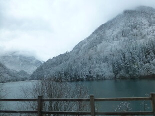 雪覆山峦下的静谧湖水