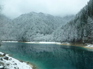 雪覆山林间的碧蓝湖水