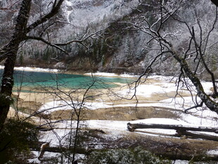 雪覆山林间的碧绿湖水