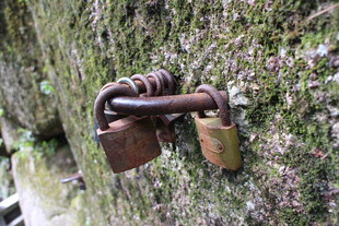 古老铁锁挂于斑驳石墙