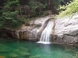 山间清澈瀑布下的碧绿潭水