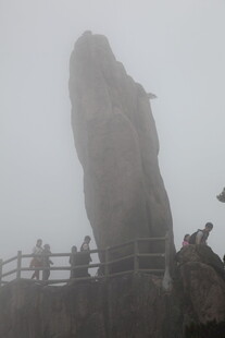 雾中奇石旁的游客身影