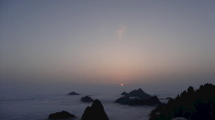 海上日出 礁石隐于晨雾中