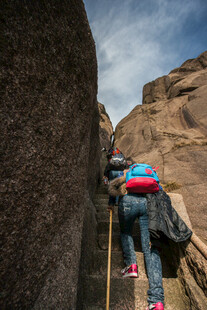 女子攀岩于陡峭岩壁间