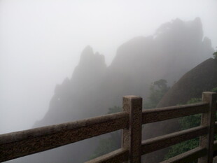 雾中峻岭旁的木质护栏