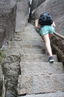 游客艰难攀爬陡峭石阶