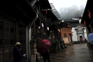 烟雨古巷中的撑伞行人