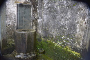 古老石制物件立于斑驳墙边