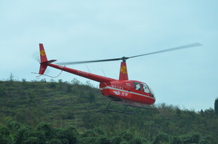 红色直升机翱翔于青山之上