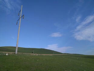 草原上的电线杆与蓝天