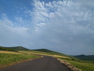 蜿蜒公路穿行于绿野蓝天