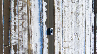 雪地公路上行驶的孤独汽车