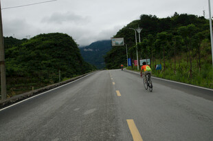 公路骑行者穿行青山间