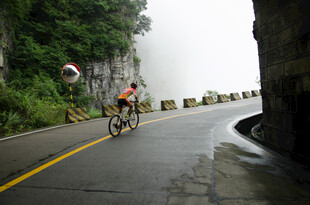 雨中骑行者穿行山间公路