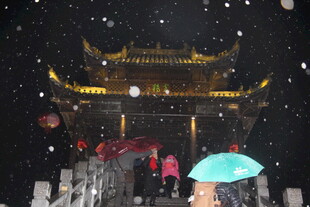 雪夜古牌坊下的撑伞行人