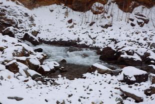 雪覆溪流间的嶙峋岩石