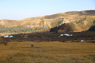 山间开阔草地与远处房屋