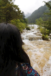 女子赏湍急山间溪流