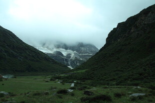 山间绿野与云雾中的雪山