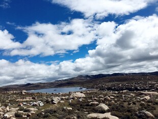 蓝天白云下的湖畔岩石景