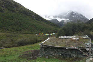 山间小屋与远处雪山美景
