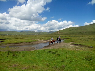 草原骑行队伍穿越溪流
