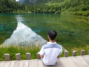 男孩静赏湖畔青山美景
