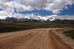 旷野土路与远处雪山景观