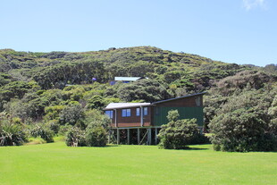 山间绿草地旁的精致小屋