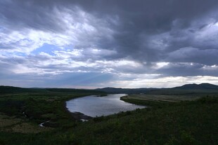 乌云下的静谧湖泊与绿地