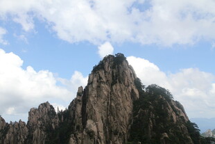 巍峨山峰耸立于蓝天白云间