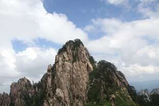 巍峨高山耸立于蓝天白云间