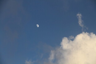 蓝天中云朵旁的一弯新月