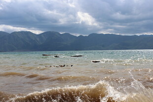 海边翻涌浪花与远山景色