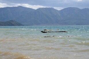 海边浅滩上的小船与远山