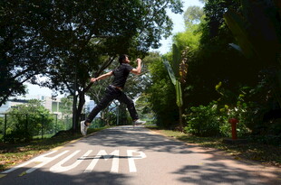 男子于林间小道活力跳跃