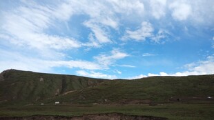 蓝天白云下的翠绿山坡