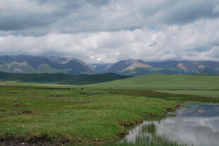 草原溪流与远处山峦景色
