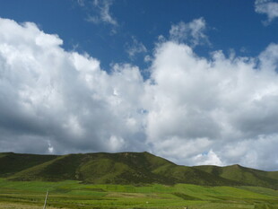 蓝天白云下的翠绿山丘