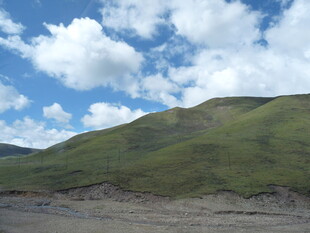蓝天白云下的翠绿山坡