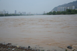 浑浊江水畔的城市与远山