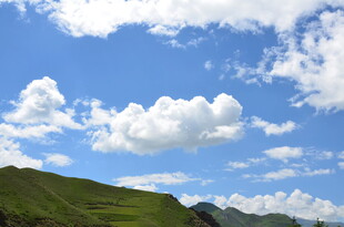 蓝天白云下的翠绿山坡